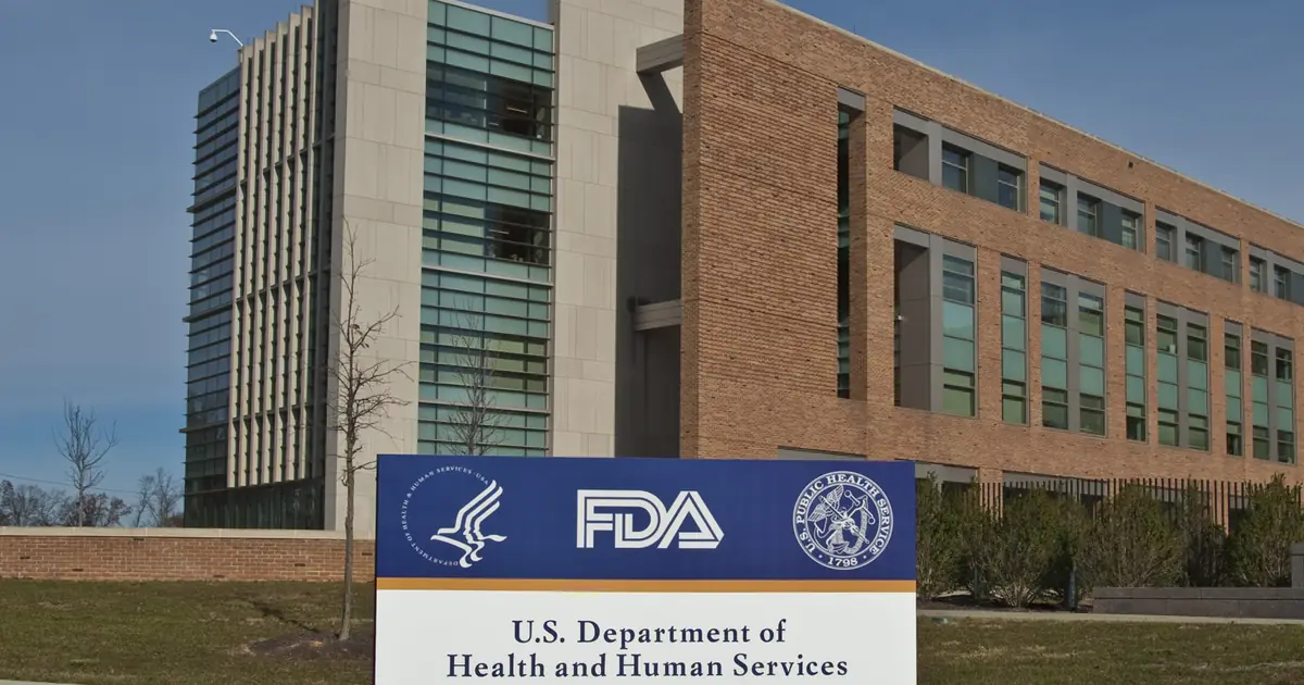 Sign reading U.S. Department of Health and Human Services, Food and Drug Administration, with a campus office building behind it.