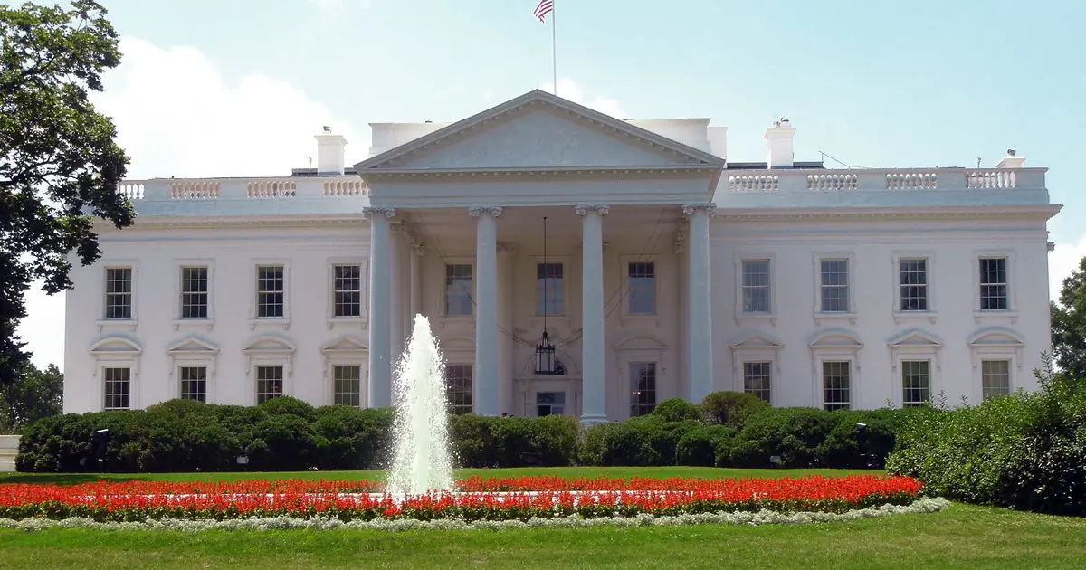The north side of the White House in Washington, D.C., with a fountain and flower beds on the lawn in front.